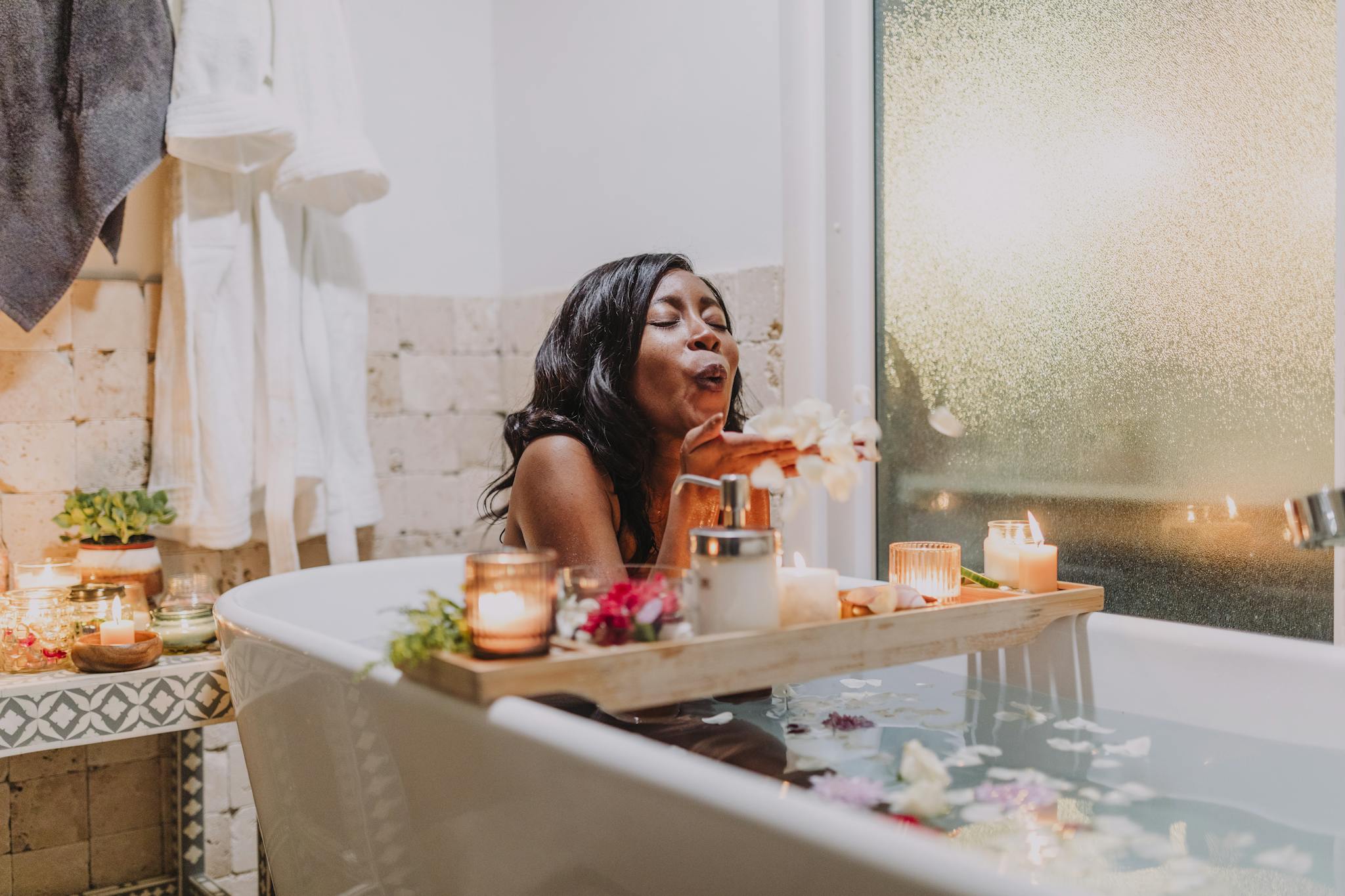 A serene woman enjoys a relaxing spa bath surrounded by candles and flowers.