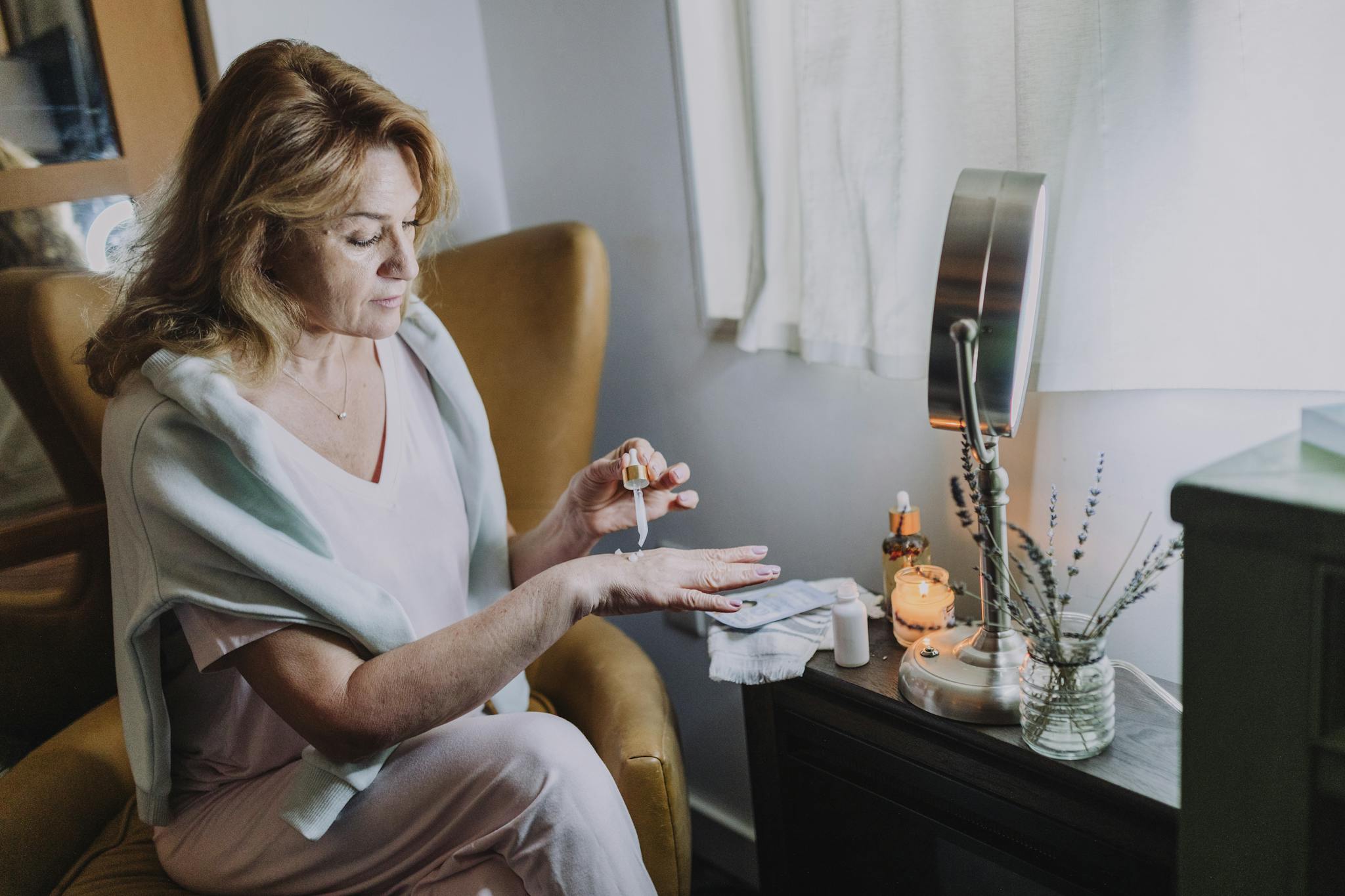 Mature woman applying skincare products in a cozy home spa setting, creating a relaxing atmosphere.